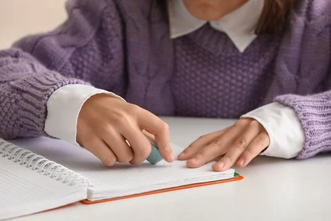 Child erasing mistake in notebook at table, closeup Foto stock