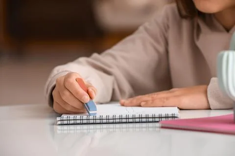 Child erasing mistake in notebook at table, closeup Foto stock