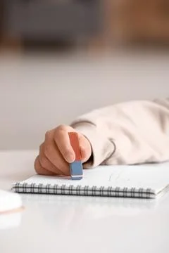 Child erasing mistake in notebook at table, closeup Foto stock