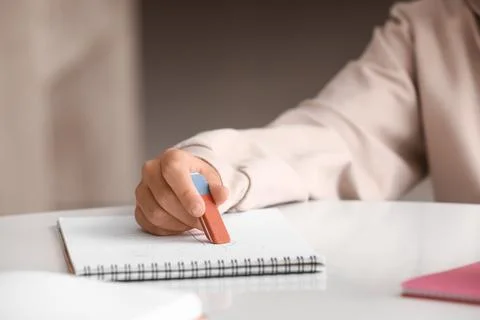 Child erasing mistake in notebook at table, closeup Foto stock