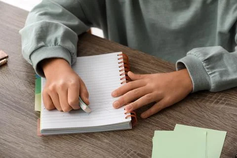 Child erasing mistake in notebook at table, closeup Foto stock