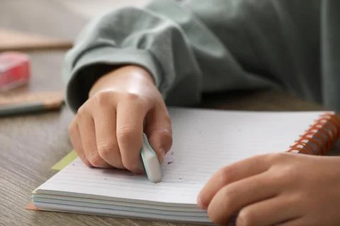 Child erasing mistake in notebook at table, closeup Foto stock
