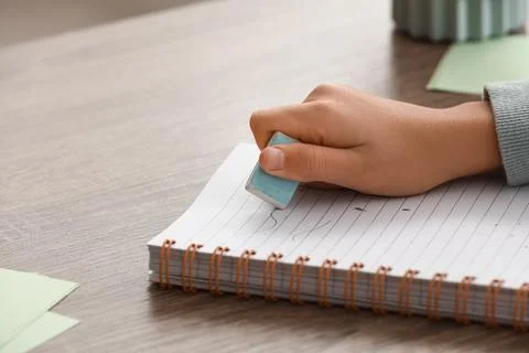 Child erasing mistake in notebook at table, closeup Foto stock