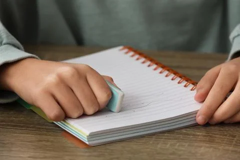 Child erasing mistake in notebook at table, closeup Foto stock
