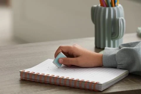 Child erasing mistake in notebook at table, closeup Foto stock
