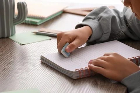 Child erasing mistake in notebook at table, closeup Foto stock