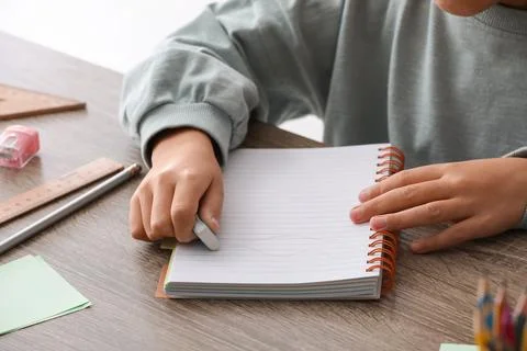 Child erasing mistake in notebook at table, closeup Foto stock