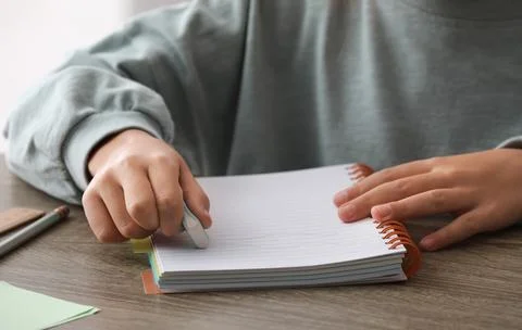 Child erasing mistake in notebook at table, closeup Foto stock