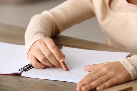 Child erasing mistake in notebook at table, closeup Foto stock