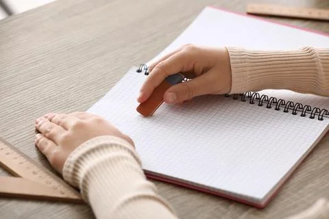 Child erasing mistake in notebook at table, closeup Foto stock