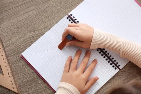 Child erasing mistake in notebook at table, top view Foto stock