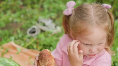 Child examines bread, Child bites bread and looks shy during family outing Stock Footage 324869022