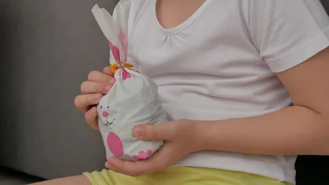 The child examines a gift bag with a rabbit, turns it around. A surprise for Eas Stock Footage 254069879