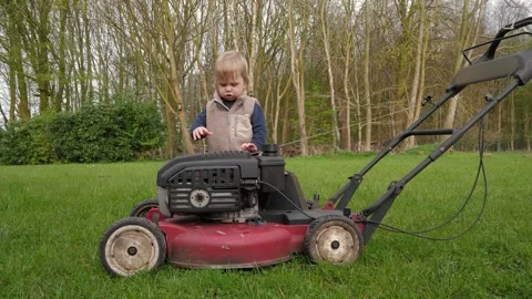 A child examines a lawn mower Stock Footage 322199887