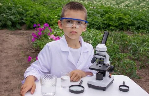 A child examines water using a magnifying glass Stock Photos