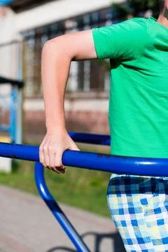 Child exercising on outdoor parallel bars.  Building strength and enjoying .. Stock-Fotos