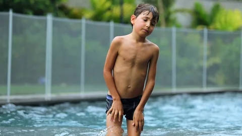 Child exits swimming pool. Young boy walks out of the water after having play