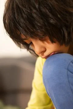 Child experiencing sadness while sitting alone and contemplating Stock Photos