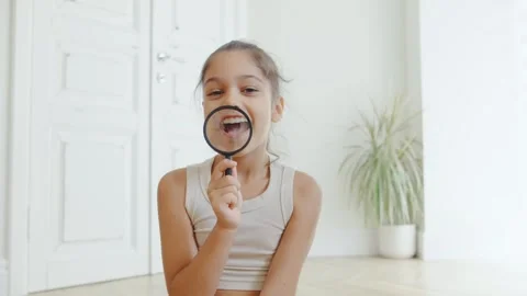 Child exploring and learning with a magnifying glass in a bright and spacious Stock Footage 315551875