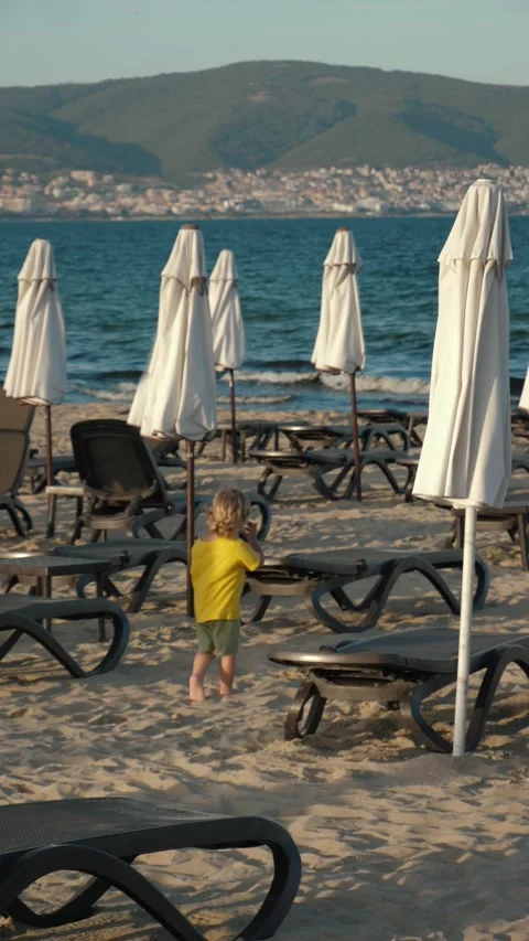 Child Exploring Beach with Umbrellas and Lounge Chairs Stock Footage 307720946