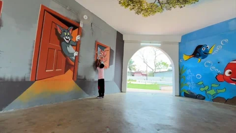 Child Exploring Cartoon-Themed Wall Art Inside Public Park Pavilion in Dibrugarh 스톡 동영상 334773923