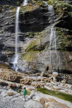 Child exploring large waterfalls flowing down rocky cliffs Stock Photos