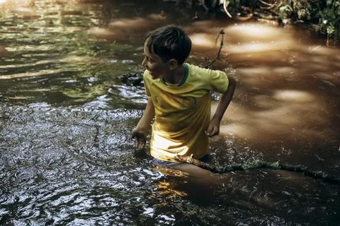 Child Exploring Muddy Stream in Summer Adventure Stock Photos