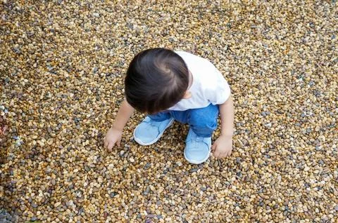 Child Exploring Pebbled Ground Stock Photos