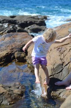 Child Exploring Rocks and Water at Seaside with Curious Steps Stock Photos