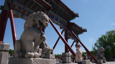 Child with face mask touching stone lion in Beihai Park, Beijing, China. Stock Footage 130993124
