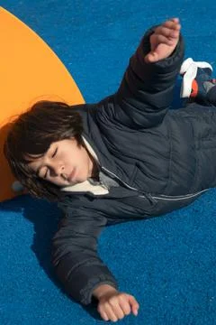 Child falling on blue playground surface after an accident Stock Photos