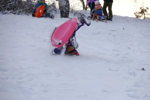 Child falling headfirst into deep snow while sledding Stock Photos