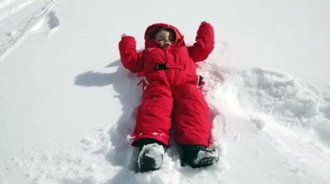 Child falling in the snow and draws angel Stock Footage