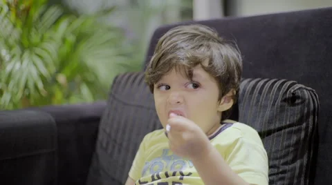 Child feeding himself while watching TV Stock Footage 59103888