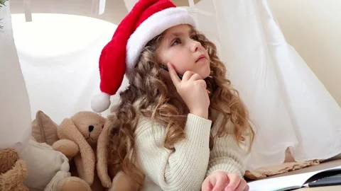 Child in festive hat joyfully creating holiday artwork indoors 스톡 동영상 296324221