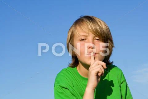 Child with finger to lips to ask for quiet or silence Stock Photos