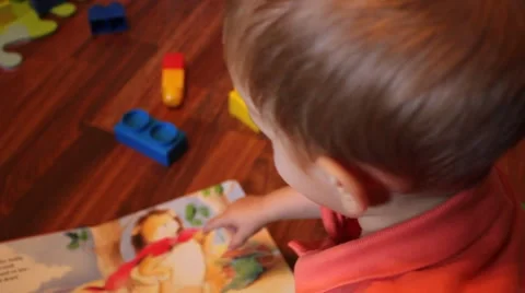 Child flips through a book while playing in his room Stock Footage 44445766