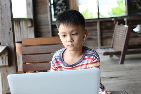 Child Focused on Laptop in Rustic Setting Stock-Fotos