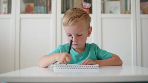 Child focused on practicing handwriting in school. Small child scribbling w.. Stock Footage 340726375