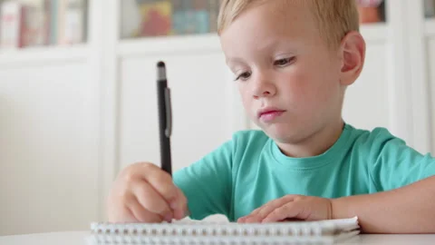 Child focused on practicing handwriting in school. Small child scribbling w.. Stock Footage 340727786