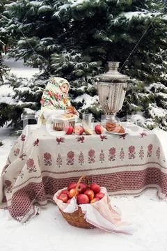 Child in a fur coat and in a scarf sit near samovar in hands big pie. Maslenitsa Stock Photos