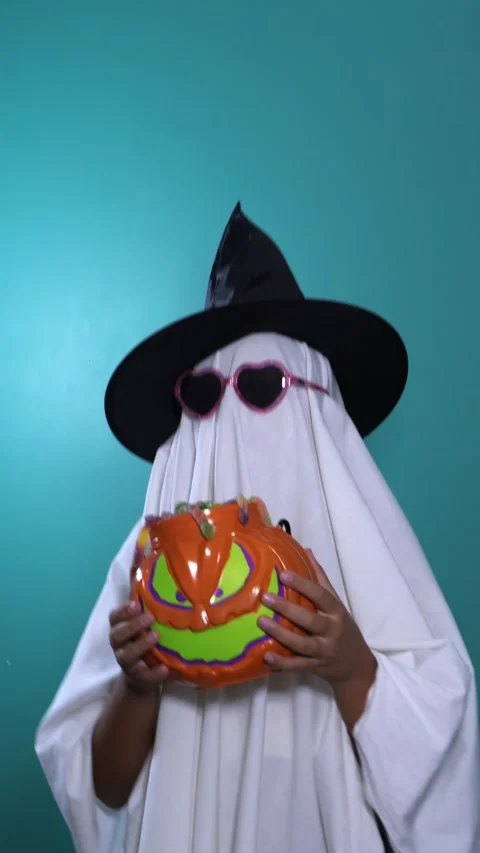 Child in ghost costume holds pumpkin candy bucket for Halloween trick or treat 스톡 동영상 342521501