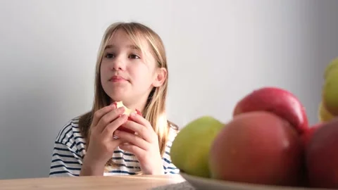 Child girl blonde eats an apple on a white background. Video Delicious ripe Stock Footage 212464154