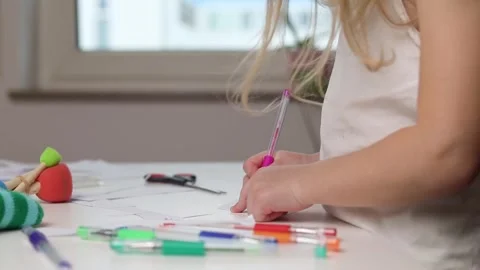 Child girl draws with a pen while standing at the table Video stock 242873535