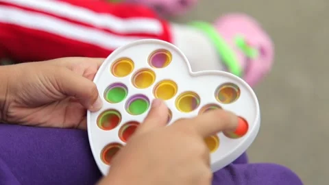 Child girl hands playing with popular silicone anti-stress toy pop it Stock Footage 159945853