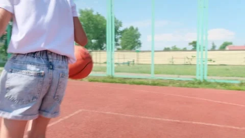 Child girl practicing exercise hitting basketball ball training on court in city Stock Footage 282081735