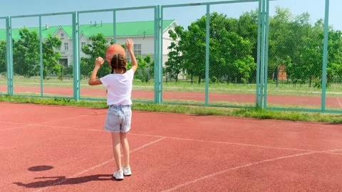 Child girl practicing exercise hitting basketball ball training on court in city Stock Footage 282081827