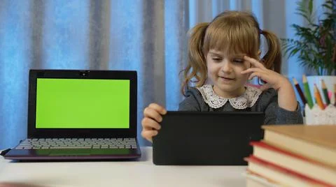 Child girl pupil doing homework with teacher using digital tablet at home Foto stock