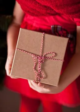 Child girl in red dress holding a Christmas gift box in a hands Stock Photos