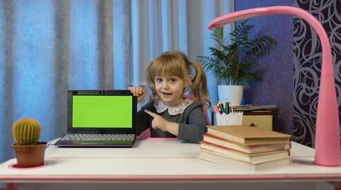 Child girl studying e-learning, distance education, kid pointing at laptop green Stock Photos
